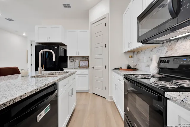 a kitchen with granite countertop a stove top oven a sink a counter space and cabinets