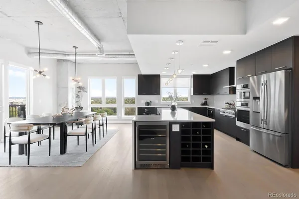 a kitchen with stainless steel appliances a stove a refrigerator a sink a stove a dining table and chairs