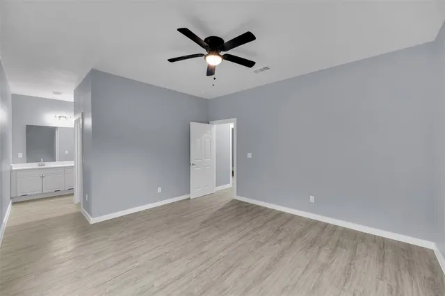 an empty room with wooden floor and ceiling fan
