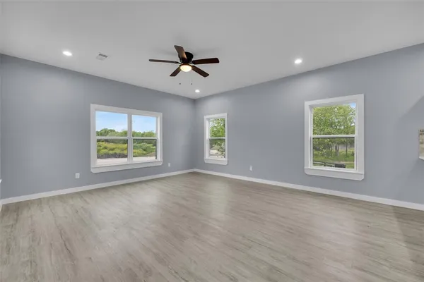 a view of an empty room with a window and wooden floor