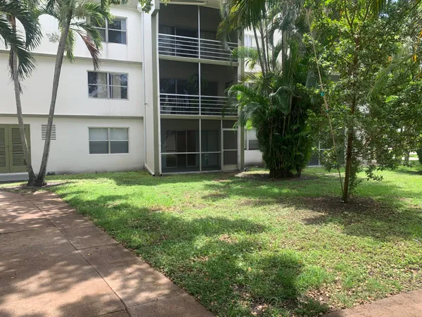 a view of a house with a yard and a large tree