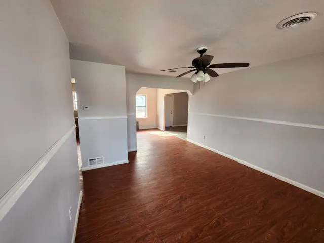 a view of a room with wooden floor a ceiling fan and staircase