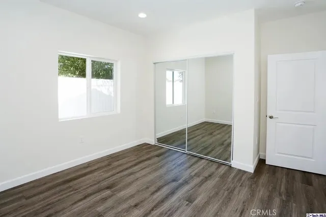 an empty room with wooden floor cabinet and windows