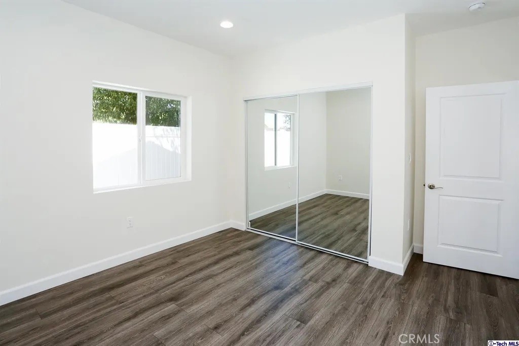 7521 Milwood Avenue Canoga Park, CA 91303 - Photo 12 of 15 an empty room with wooden floor cabinet and windows