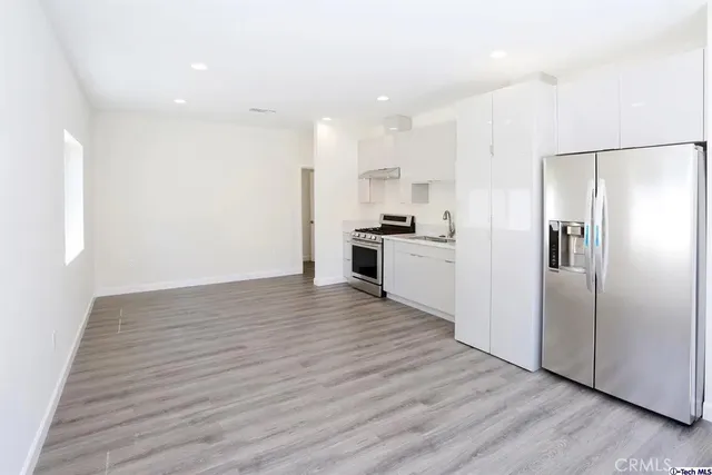 a view of a kitchen with wooden floor electronic appliances and cabinets