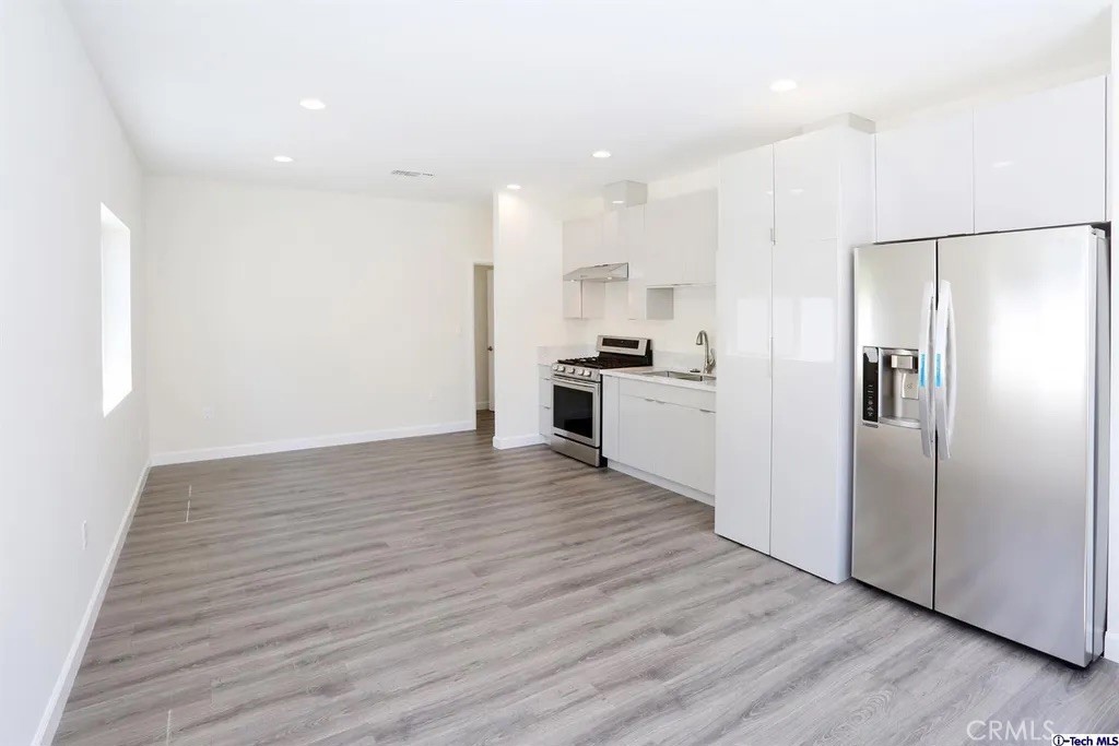 7521 Milwood Avenue Canoga Park, CA 91303 - Photo 6 of 15 a view of a kitchen with wooden floor electronic appliances and cabinets