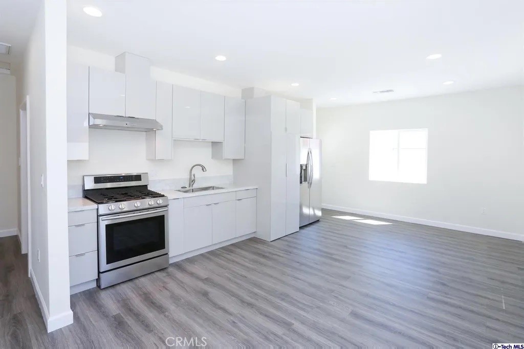 7521 Milwood Avenue Canoga Park, CA 91303 - Photo 7 of 15 a kitchen with granite countertop a sink cabinets stainless steel appliances and a window