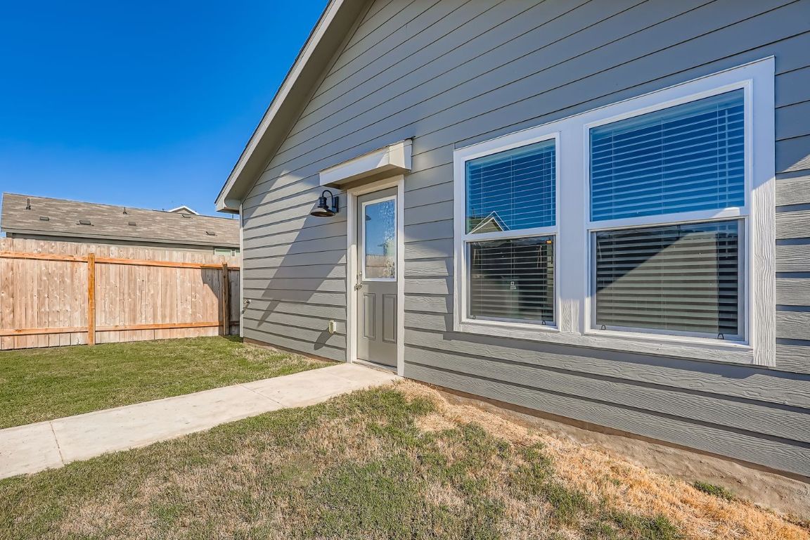210 Sormonne Loop Kyle, TX 78640 - Photo 16 of 17 a view of yellow house with a small yard and wooden fence