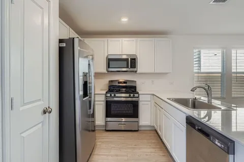 a kitchen with stainless steel appliances granite countertop a stove a sink and a refrigerator