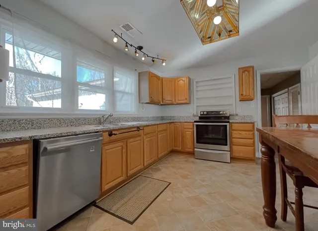 a kitchen with cabinets a sink stainless steel appliances and window