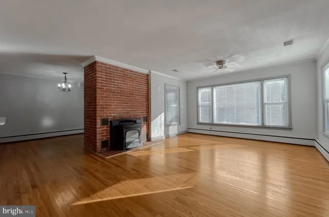a view of an empty room with wooden floor fireplace and a window