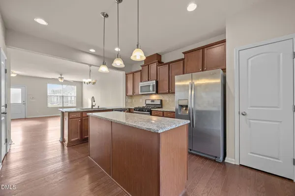 a kitchen with stainless steel appliances granite countertop a refrigerator a sink dishwasher a oven with white cabinets and wooden floor