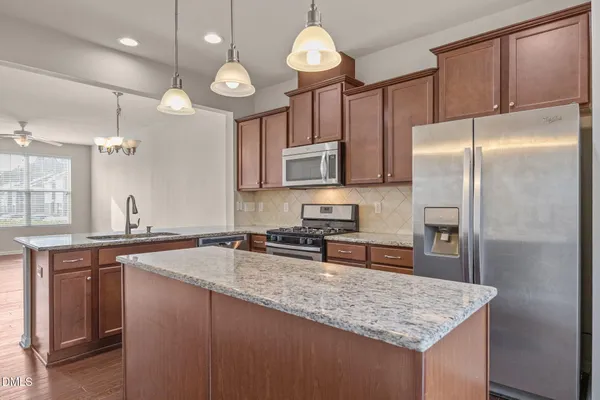 a kitchen with stainless steel appliances granite countertop a sink a refrigerator and a wooden cabinets