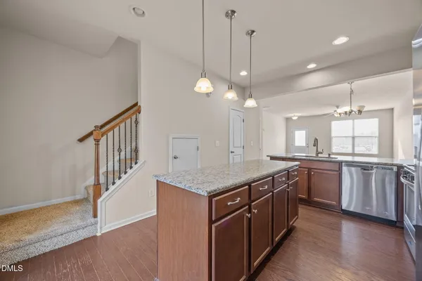 a kitchen with stainless steel appliances granite countertop a stove a sink dishwasher a refrigerator and white cabinets with wooden floor
