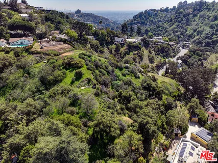 an aerial view of residential houses with outdoor space and trees