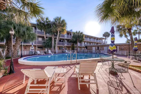 a view of a swimming pool with a patio and palm trees