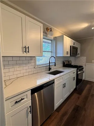 a kitchen with stainless steel appliances a sink cabinets and a wooden floor