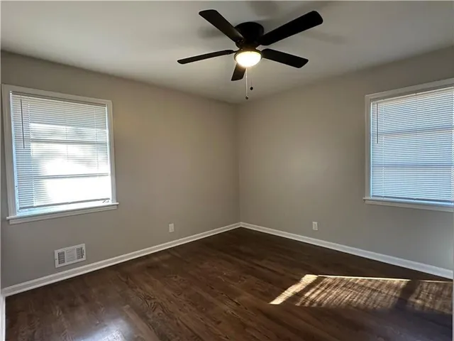 en empty room with wooden floor and windows