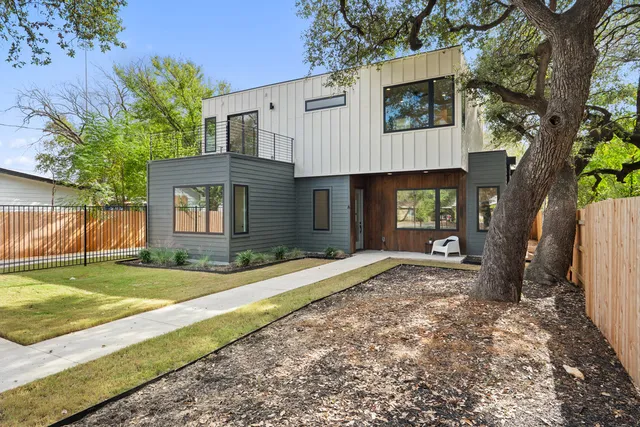 a view of a house with a yard and large tree
