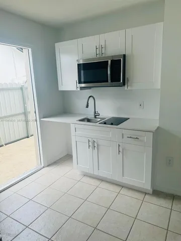 a kitchen with white cabinets a sink and a stove with wooden floor