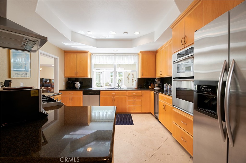 4 Lucerne, Unit 22 Newport Beach, CA 92660 - Photo 9 of 23 a large open kitchen with stainless steel appliances kitchen island granite countertop a refrigerator a stove a sink dishwasher with a dining table and chair