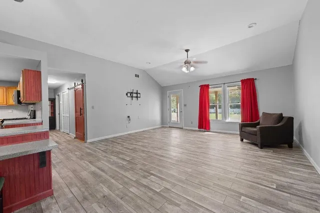 a view of an empty room with window and a kitchen