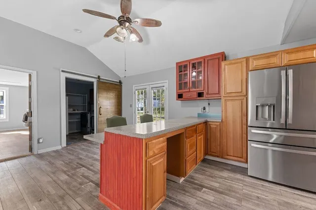 a kitchen with stainless steel appliances granite countertop a refrigerator a stove and a sink with wooden floors