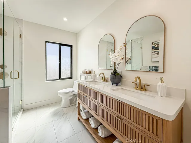 a en suite bathroom with a double vanity sink a mirror and a toilet
