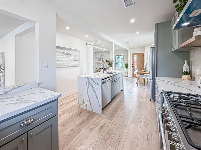 a living room with stainless steel appliances furniture wooden floor and a view of kitchen