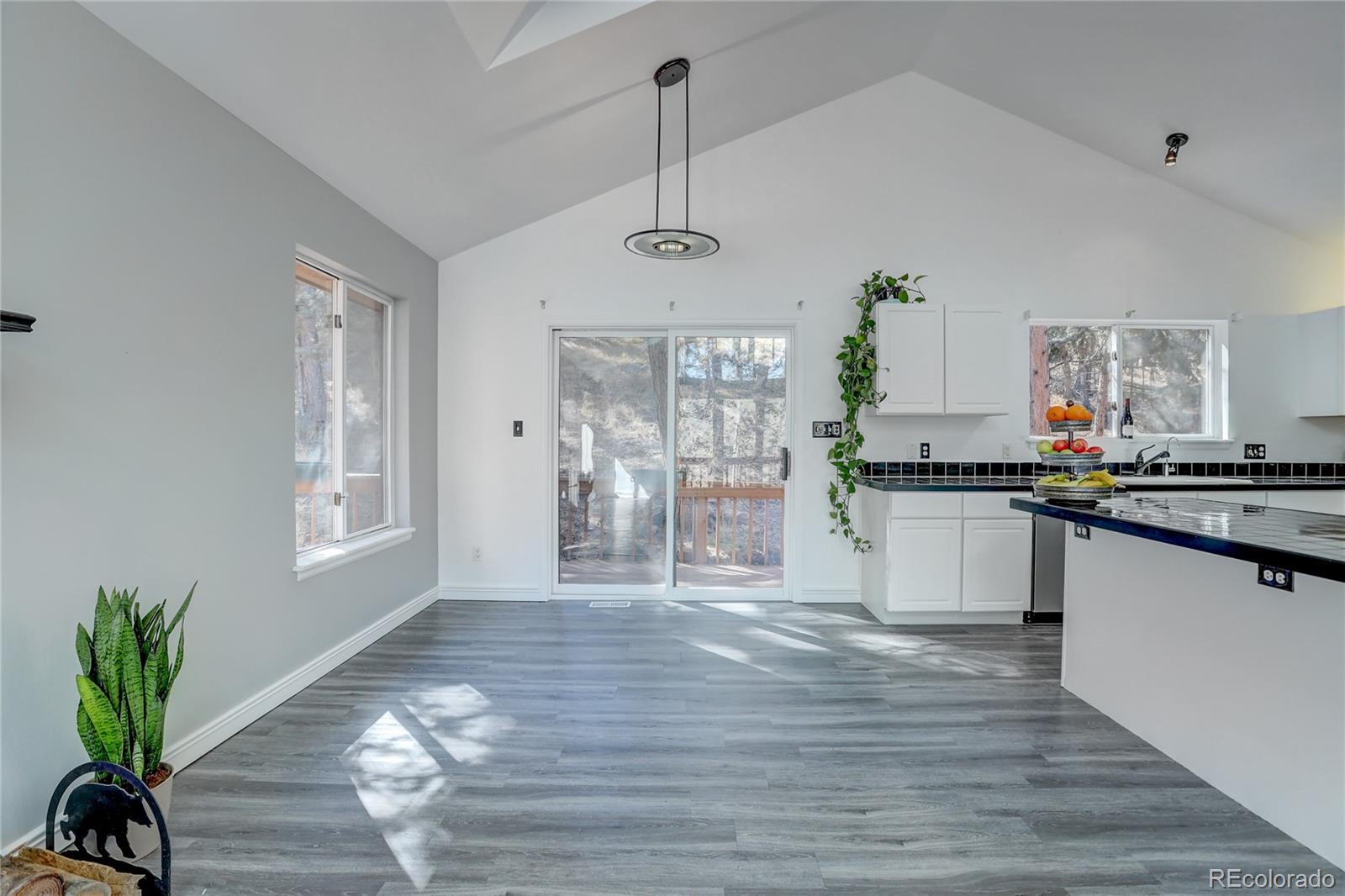 1469 Roland Drive Bailey, CO 80421 - Photo 10 of 39 a kitchen with granite countertop a stove a sink and white cabinets with wooden floor