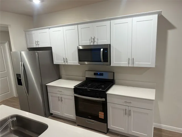 a kitchen with white cabinets and stainless steel appliances