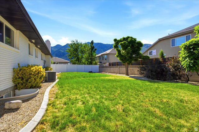 1676 East 11245 South Sandy, UT 84092 - Photo 33 of 34 Expansive backyard featuring a lush lawn, a white privacy fence, and mature trees with great mountain views.