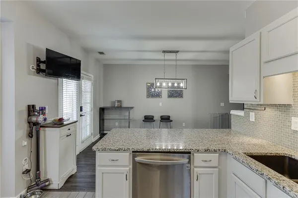 a kitchen with granite countertop a sink stainless steel appliances and white cabinets