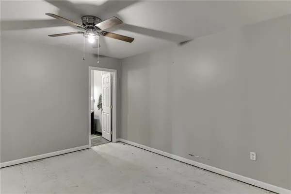 an empty room with a chandelier fan and windows