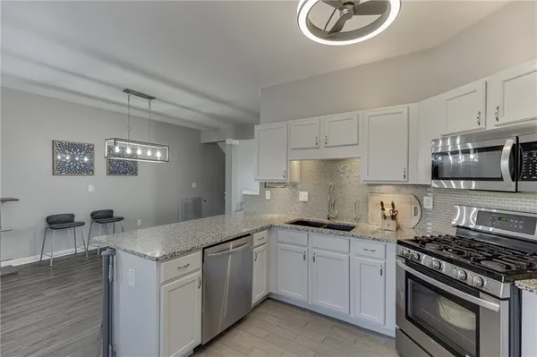a kitchen with granite countertop a sink stainless steel appliances and cabinets