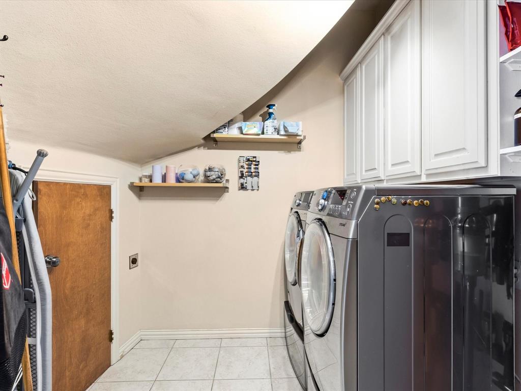 1615 Roma Lane Allen, TX 75013 - Photo 19 of 36 Laundry area featuring extra storage space, upper cabinetry, two wall-mounted shelves, and light-toned tile flooring