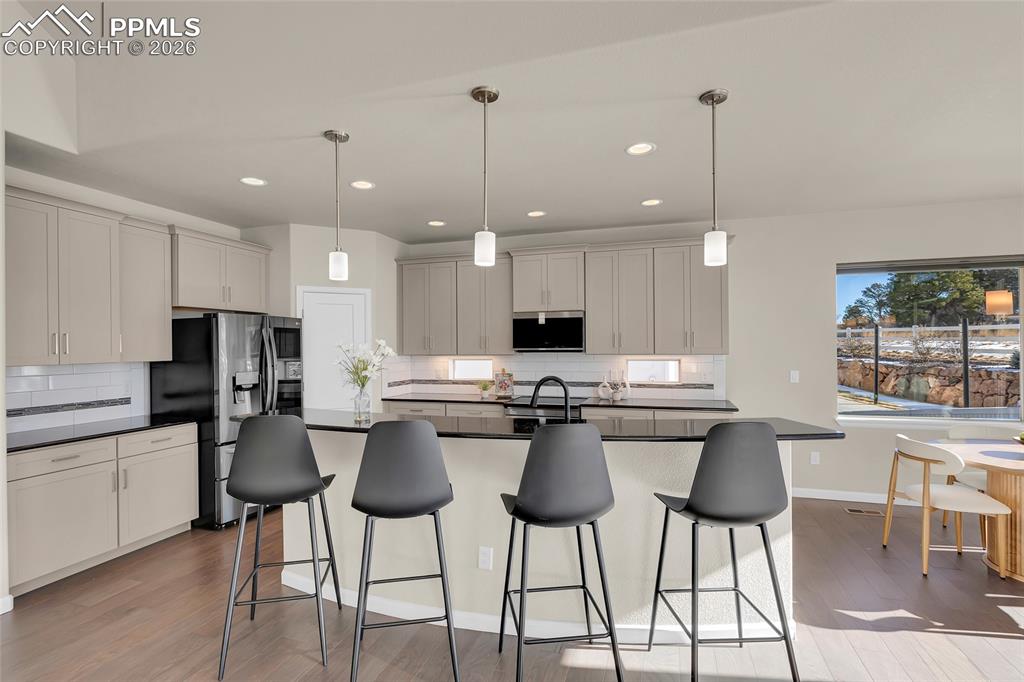 11830 Alydar Loop Colorado Springs, CO 80921 - Photo 14 of 37 a kitchen with stainless steel appliances kitchen island granite countertop a dining table chairs and white cabinets