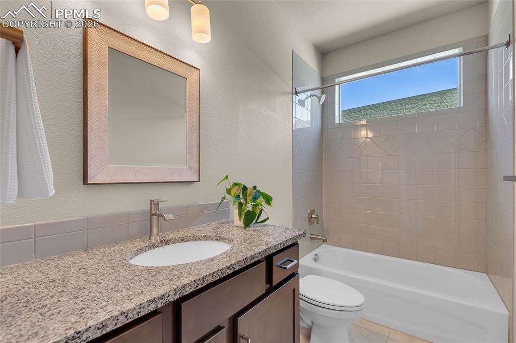 11830 Alydar Loop Colorado Springs, CO 80921 - Photo 25 of 37 a bathroom with a granite countertop sink a toilet a mirror and shower