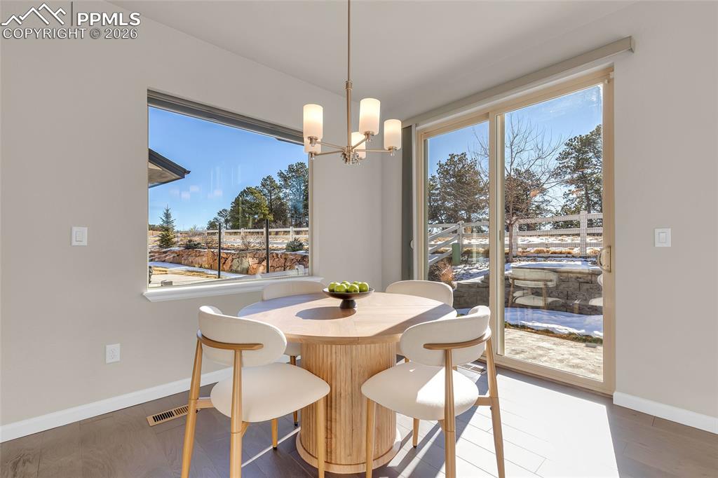 11830 Alydar Loop Colorado Springs, CO 80921 - Photo 8 of 37 a dining room with wooden floor a chandelier a glass table and chairs
