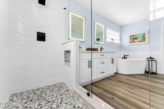 a spacious bathroom with a double vanity sink mirror and bathtub