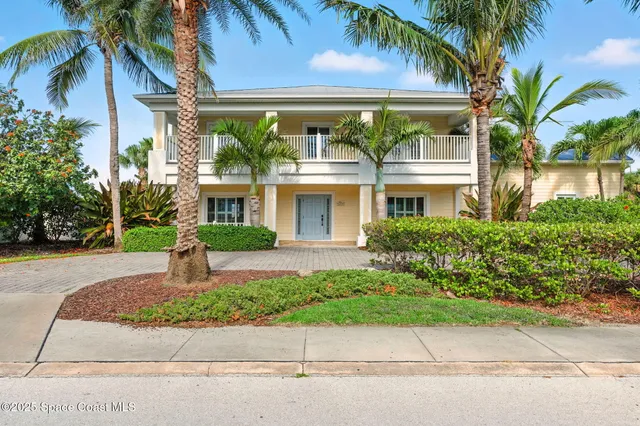 front view of a house with a yard and palm trees