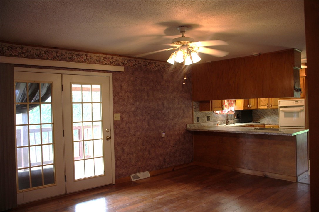 402 Canaan Road Marshall, AR 72650 - Photo 10 of 37 Open-concept living area featuring wood-finish flooring, a ceiling fan with integrated lighting, and white French doors