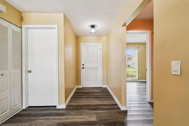 a view of a hallway with wooden floor and a bathroom