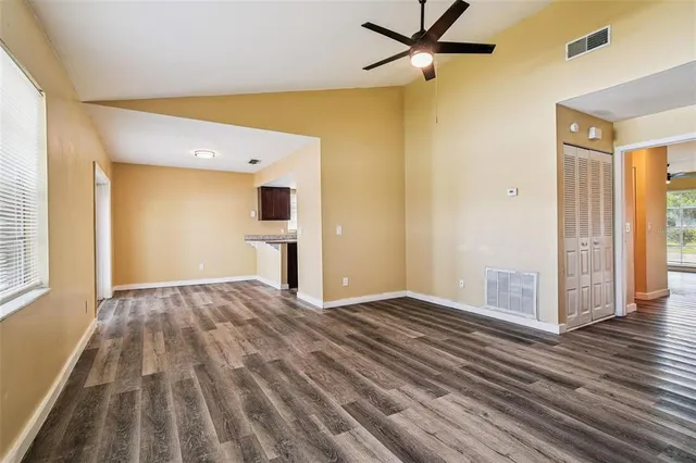 a view of empty room with wooden floor and fan