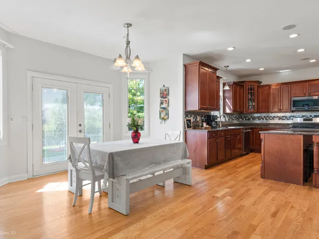 a kitchen with kitchen island granite countertop a stove a sink a refrigerator and a dining table with wooden floor