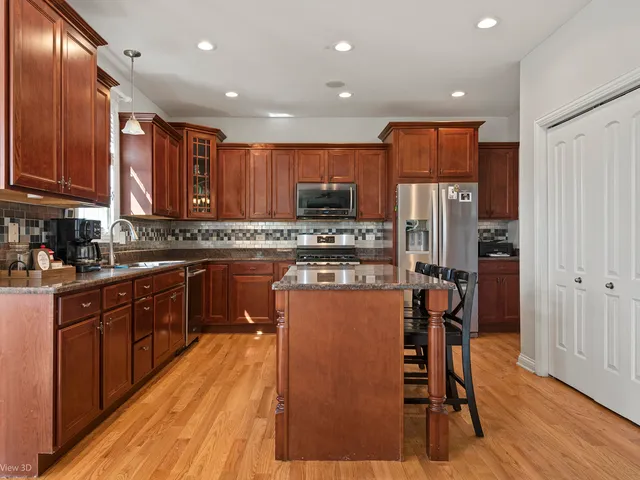 a kitchen with stainless steel appliances granite countertop a refrigerator oven a sink dishwasher and wooden cabinets with wooden floor