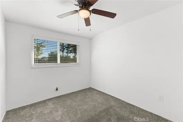 an empty room with a window and a ceiling fan