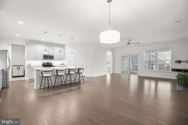 a view of a kitchen with dining table chairs wooden floor and windows