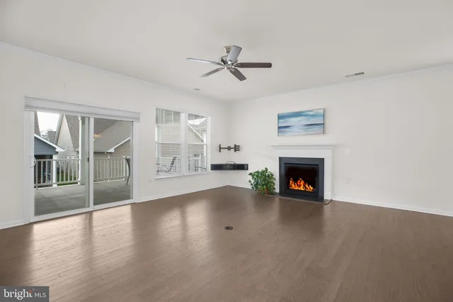 an empty room with windows fireplace and a kitchen view
