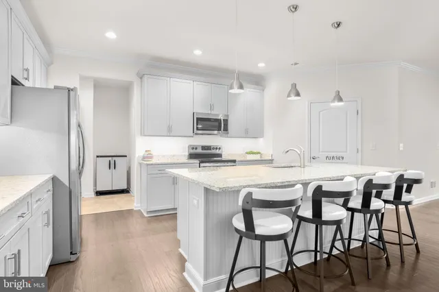 a kitchen with stainless steel appliances kitchen island granite countertop a table chairs sink and cabinets